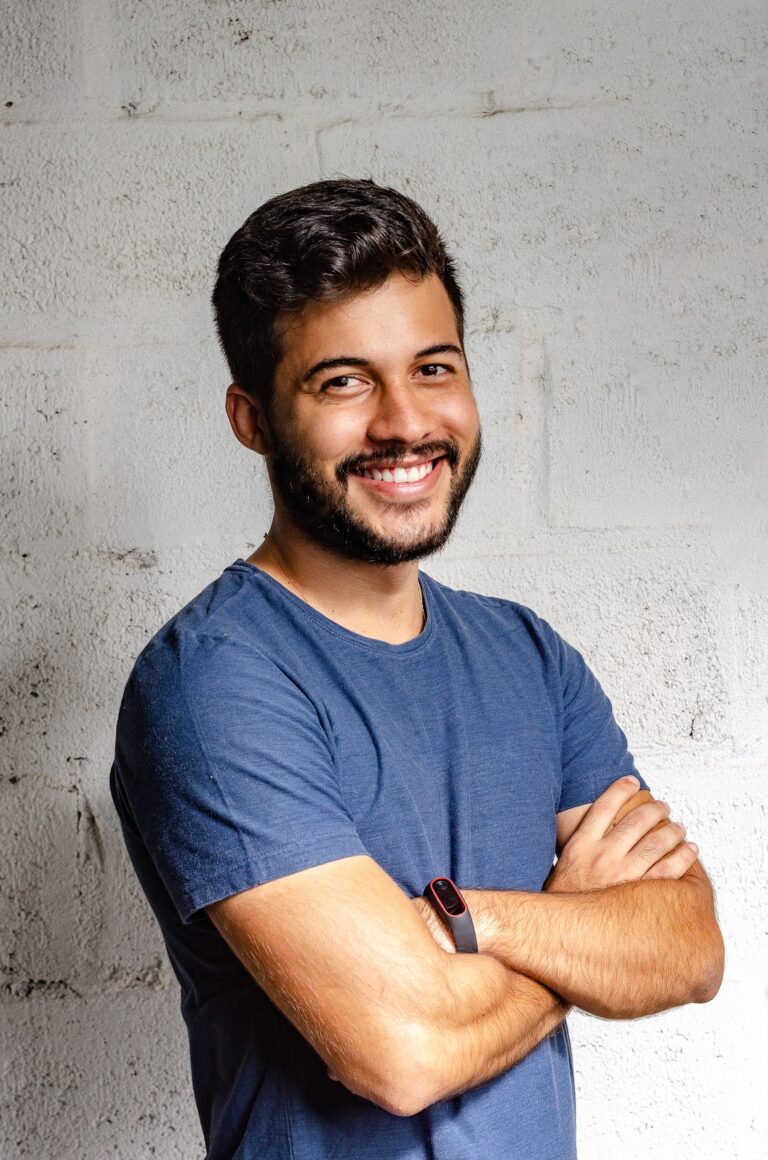 smiling man with his arms crossed standing in front of white wall